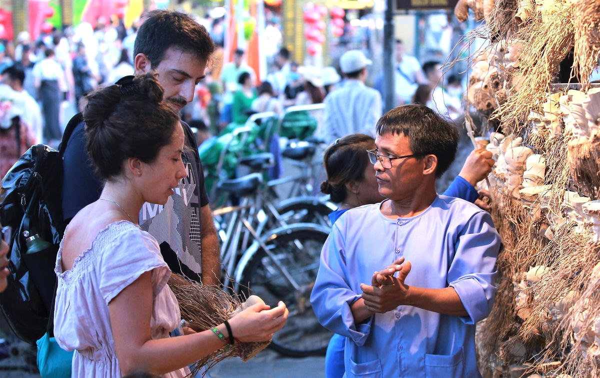 : Du khách nước ngoài hỏi mua đồ lưu niệm.