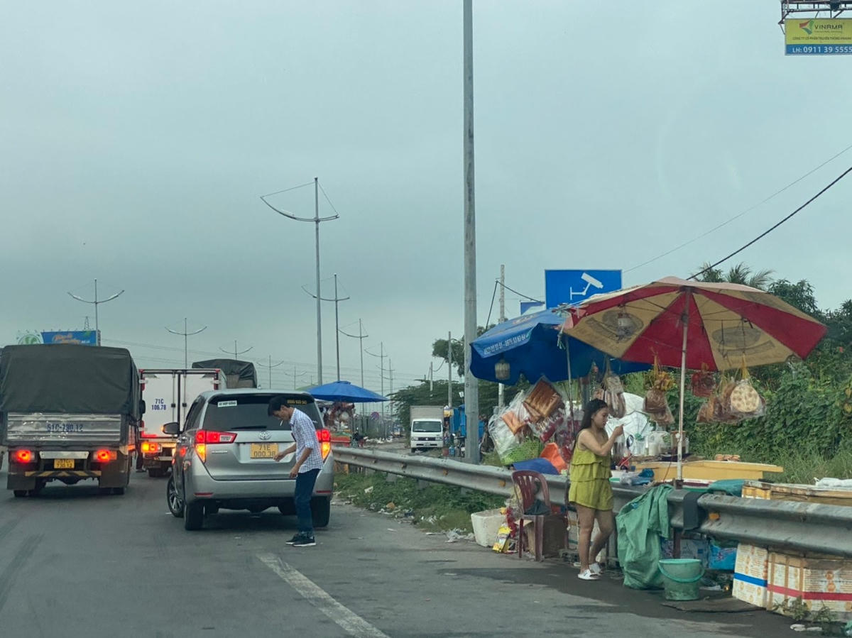 Nhiều người dựng dù (ô) bày bán đồ ăn nhanh, nước uống ở ngay trên làn đường khẩn cấp.