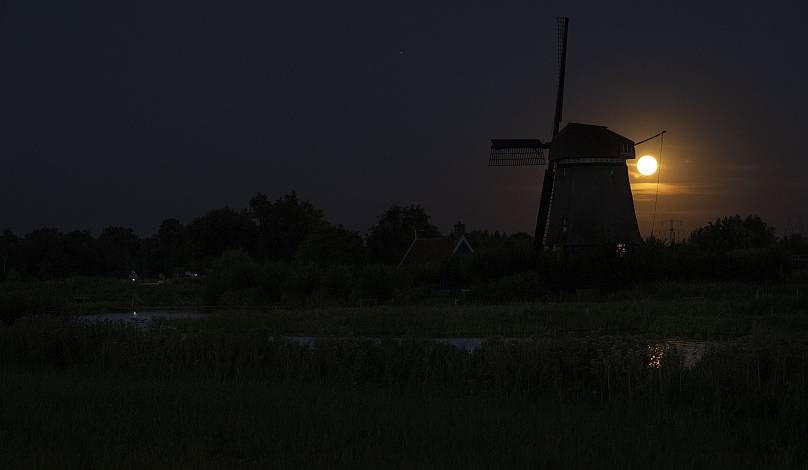 Siêu trăng lấp ló đằng sau một chiếc cối xay gió ở Oostzaan, Hà Lan. Ảnh: AP.