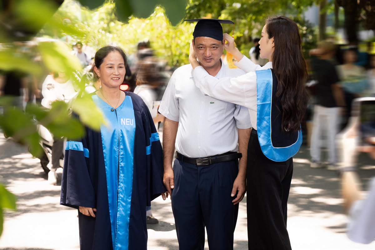 Đỗ Hà đội mũ cử nhân cho bố của mình trong ngày lễ tốt nghiệp. 