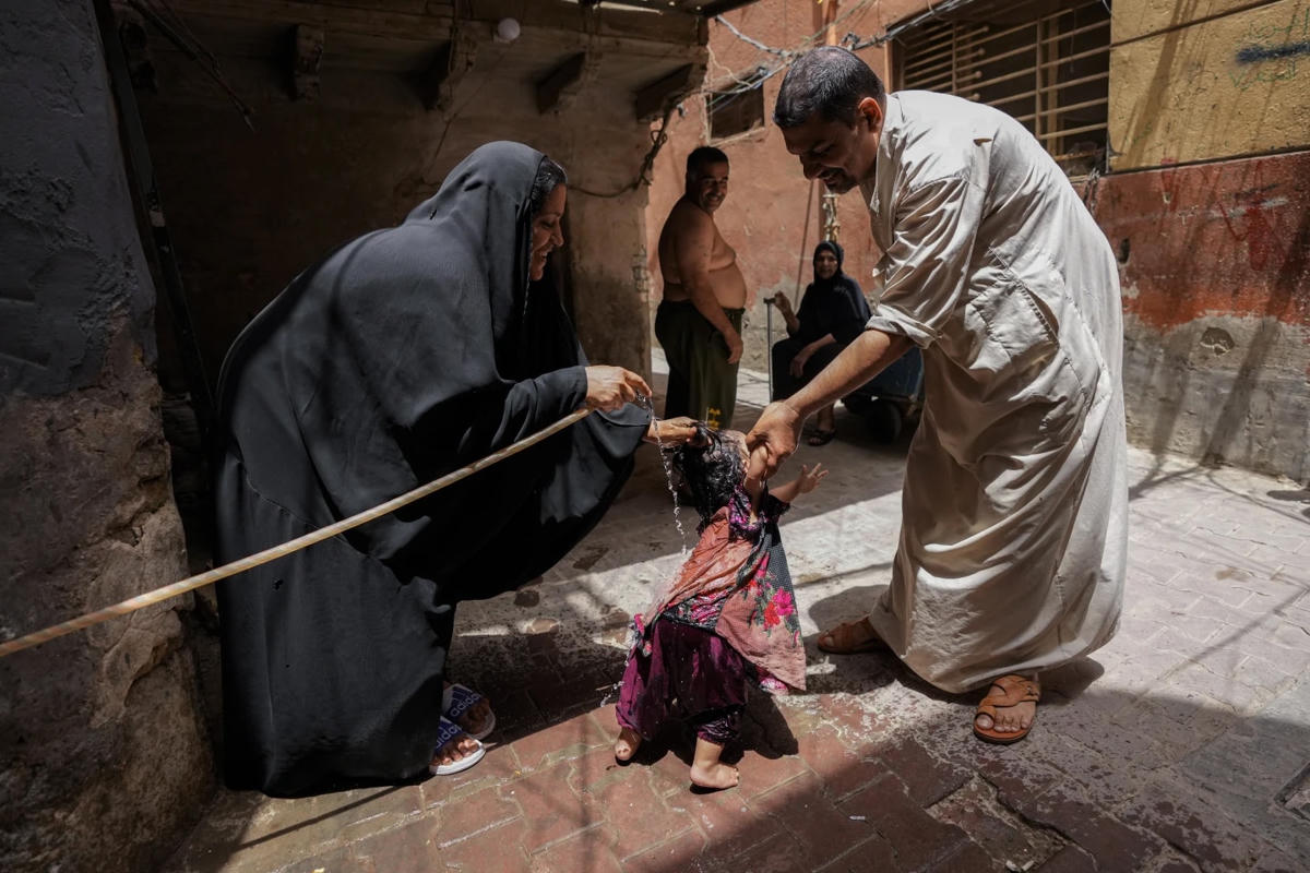 Người dân làm mát bằng nước trong một đợt nắng nóng ở khu phố al Fadhil ở Baghdad, Iraq.  