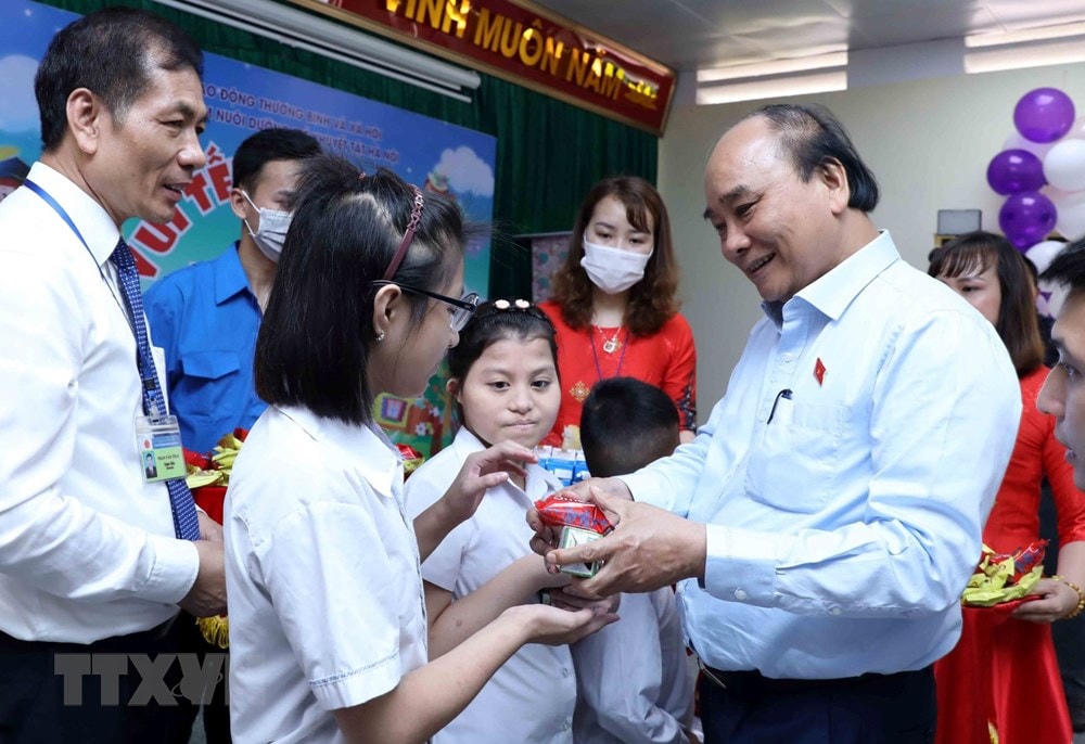 Chủ tịch nước Nguyễn Xuân Phúc tặng quà cho trẻ khuyết tật. (Ảnh: An Đăng/TTXVN).