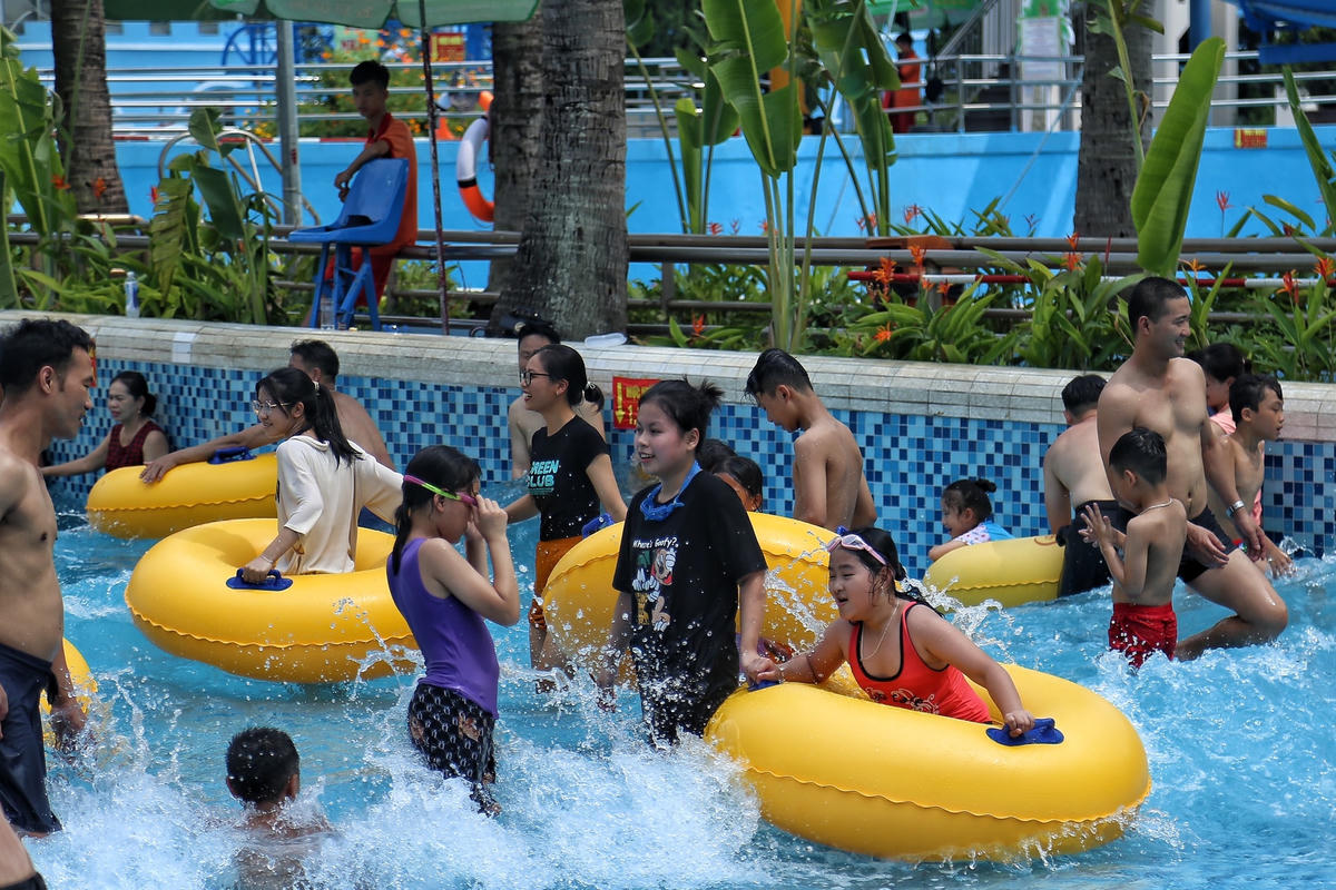 Những em nhỏ vui vẻ chơi đùa dưới bể bơi.