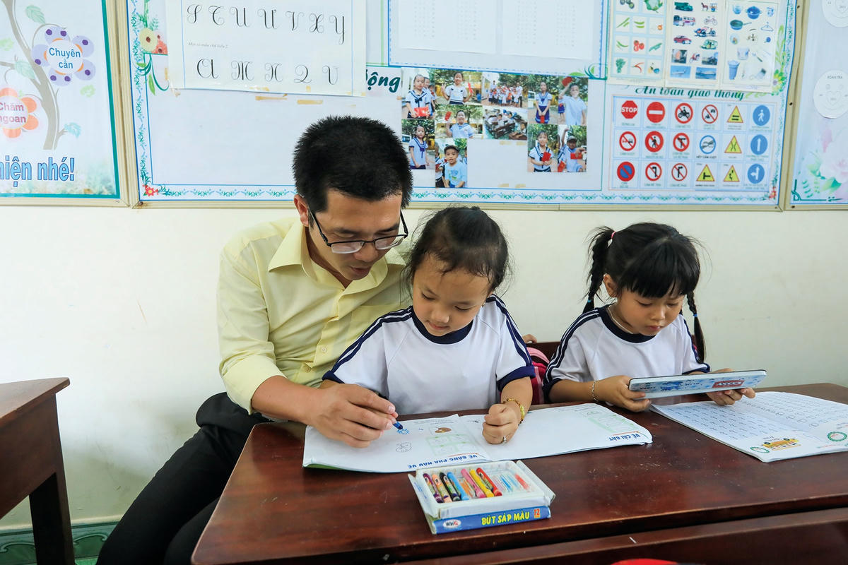 Thầy giáo Bành Hữu Tình bên các em học sinh trên đảo Trường Sa.  