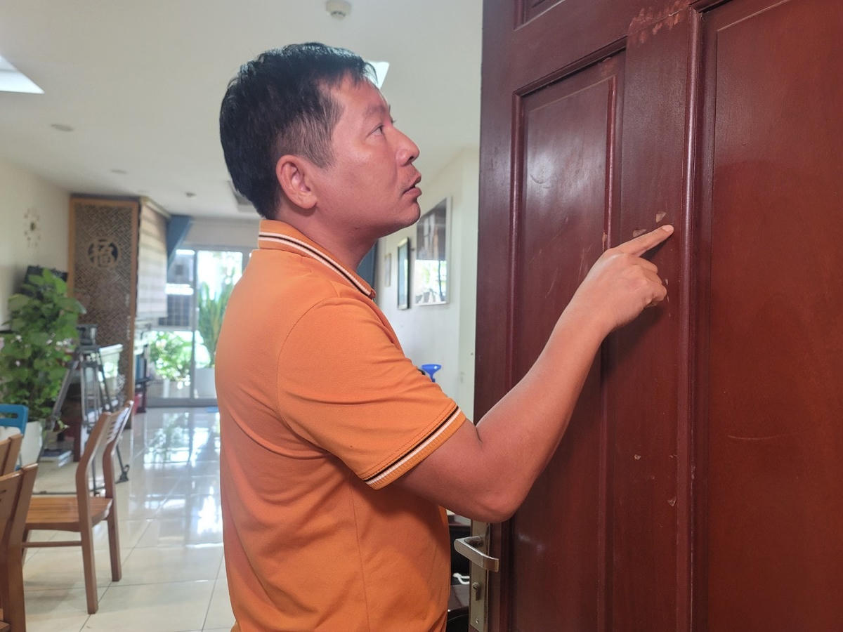 Anh L. chỉ cho phóng viên dấu vết trên cửa nhà do ông H. dùng búa đập ngày 24/4/2022.