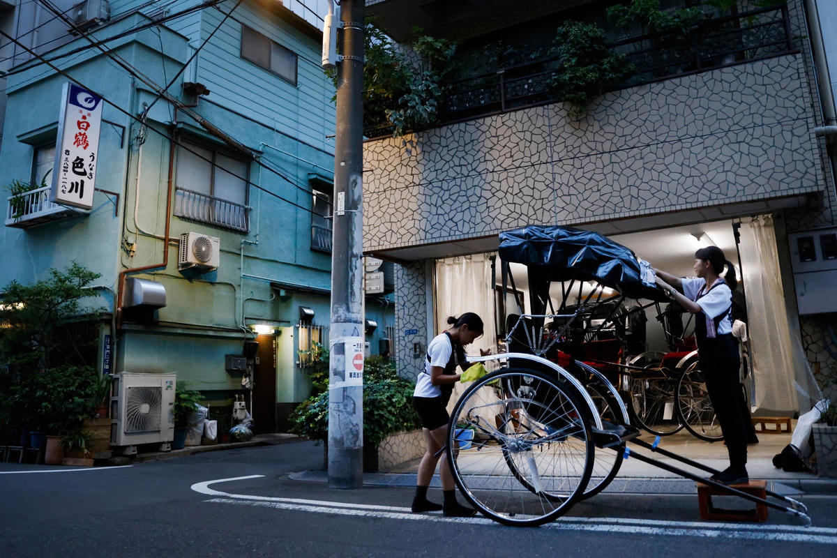 Pullers Akina Suzuki (trái) và Misato Otoshi, 30 tuổi, vệ sinh chiếc xe kéo của họ sau giờ làm việc tại một gara ở quận Asakusa, Tokyo, Nhật Bản. Ảnh: Reuters.