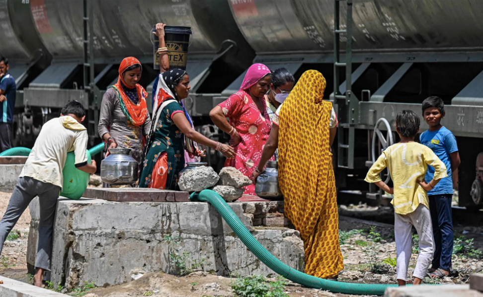 Những người phụ nữ đổ đầy nước vào bình do một đoàn tàu chở nước ở bang Rajasthan - vùng sa mạc của Ấn Độ. Ảnh: Prakash Singh / AFP / Getty Images.
