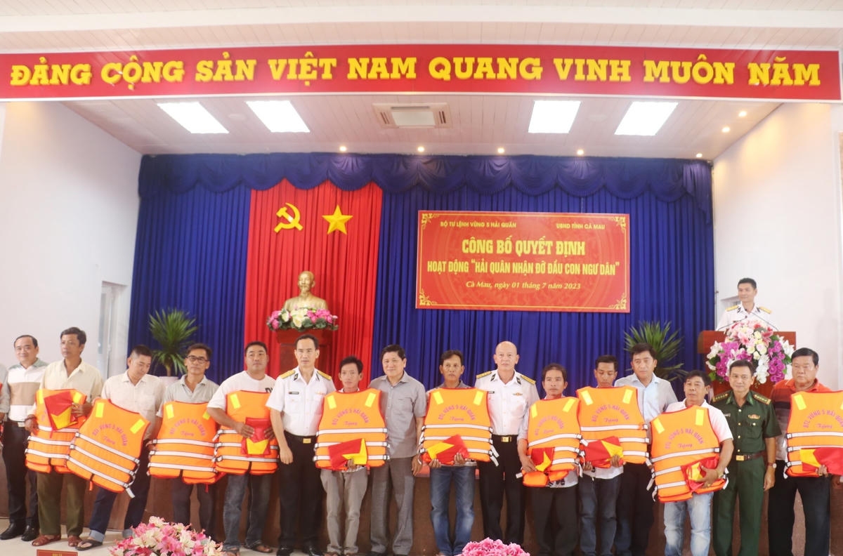 Lãnh đạo Bộ Tư lệnh Vùng 5 Hải quân và UBND tỉnh Cà Mau tặng áo phao cứu sinh và cờ Tổ quốc cho ngư dân.