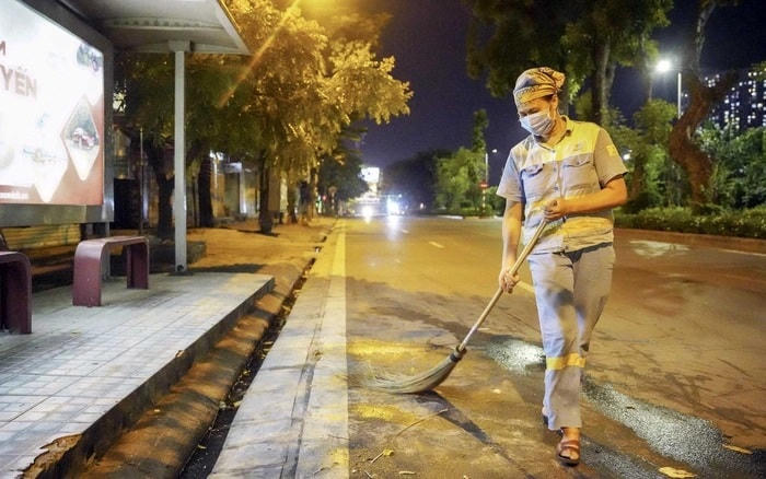 Chị Nguyễn Thị Kim Nga (50 tuổi, trú tại xã Tam Hiệp, huyện Thanh Trì), quét dọn đường phố trước điểm xe buýt 470 đường Láng, Hà Nội. Nguồn: PNVN.