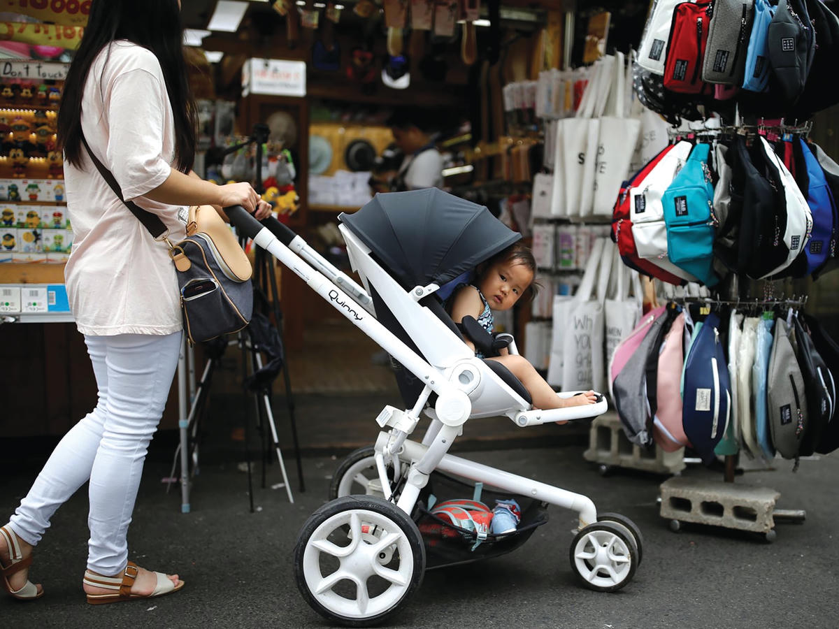 Một phụ nữ đưa con đi dạo tại khu Hongdae, Seoul, Hàn Quốc. ẢNH: REUTERS.  
