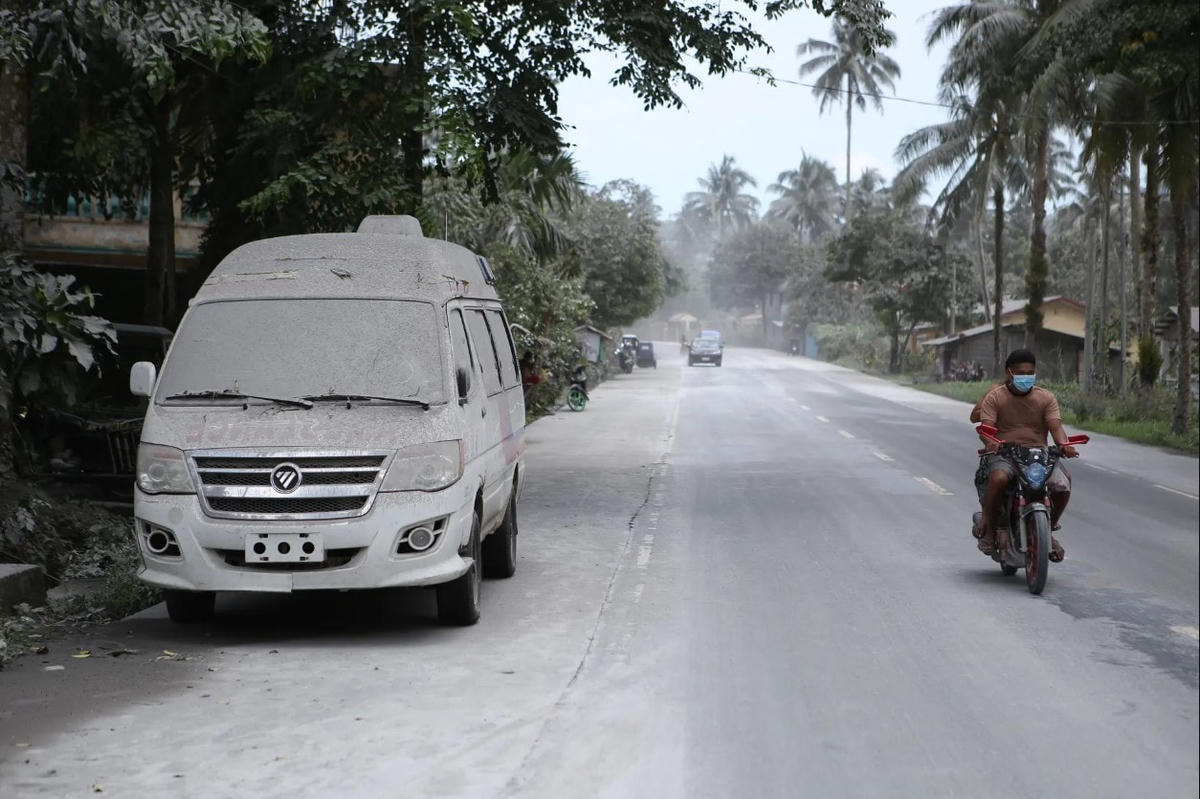 Một người đi xe máy đi qua chiếc xe cấp cứu phủ đầy tro bụi. Ảnh: Getty Images.