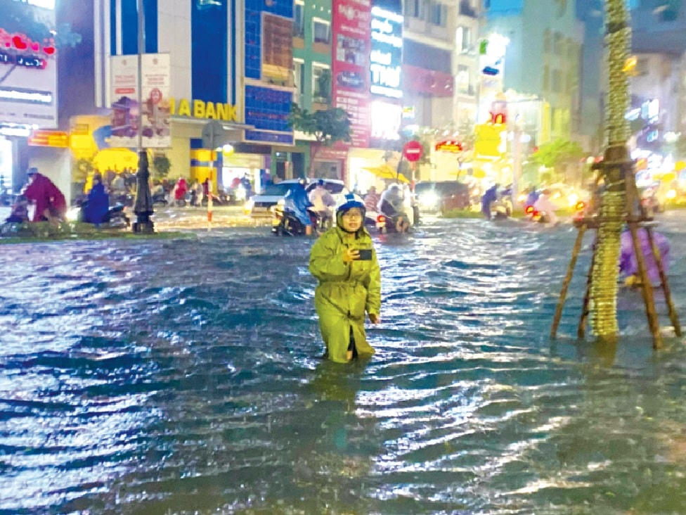 Nữ phóng viên trẻ Mai Thị Xuân Quỳnh của Văn phòng đại diện miền Trung báo Sài Gòn Giải phóng tác nghiệp trong trận mưa ngập lịch sử ở Đà Nẵng ngày 14/10/2022.