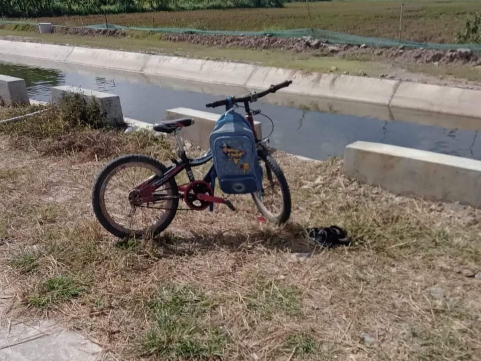 Chiếc xe của em học sinh gần mương nước.