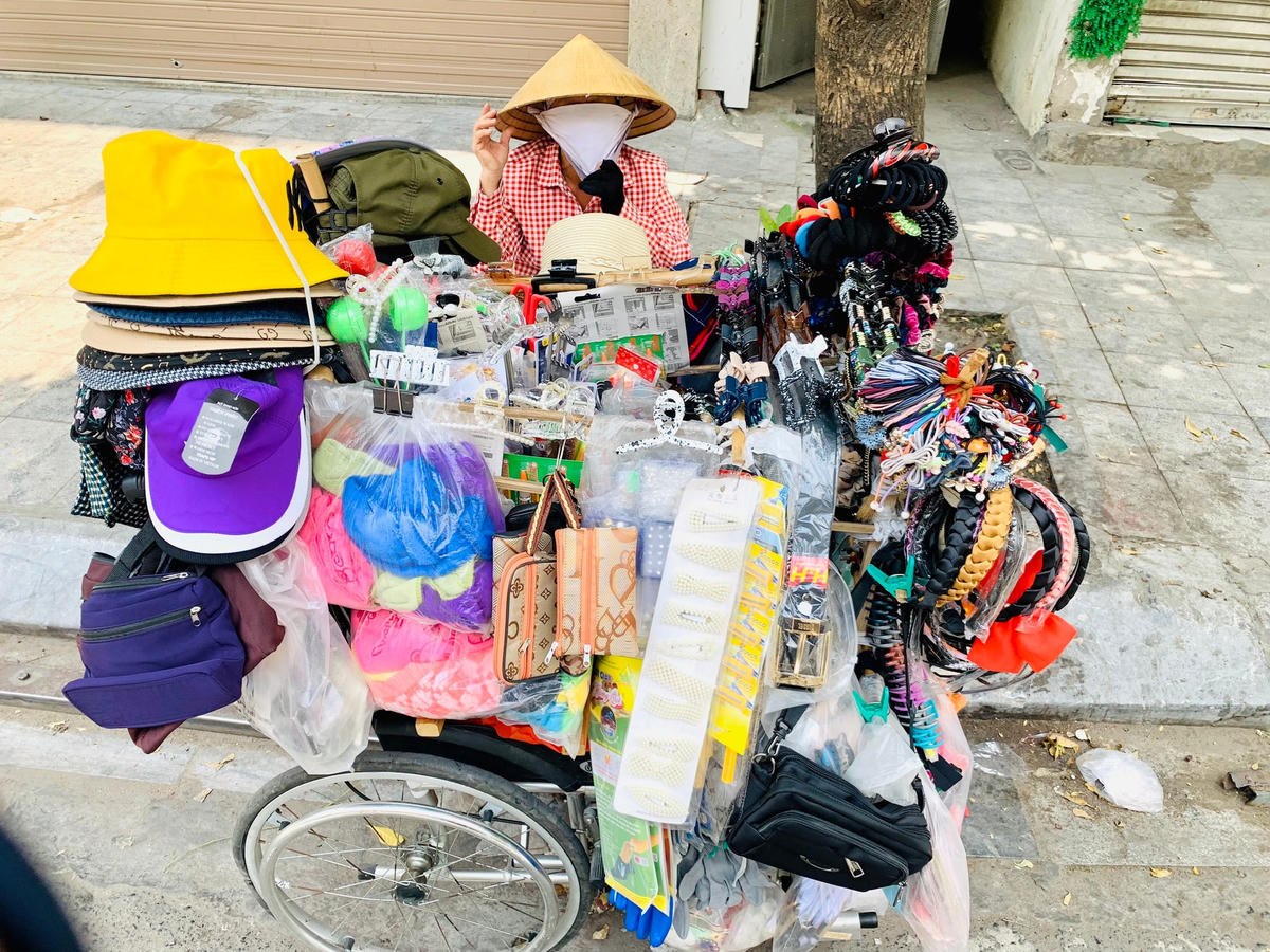Chị Thu (45 tuổi, quê Hưng Yên) che mặt kín mít để tránh nắng bên gánh hàng giữa trưa nắng.