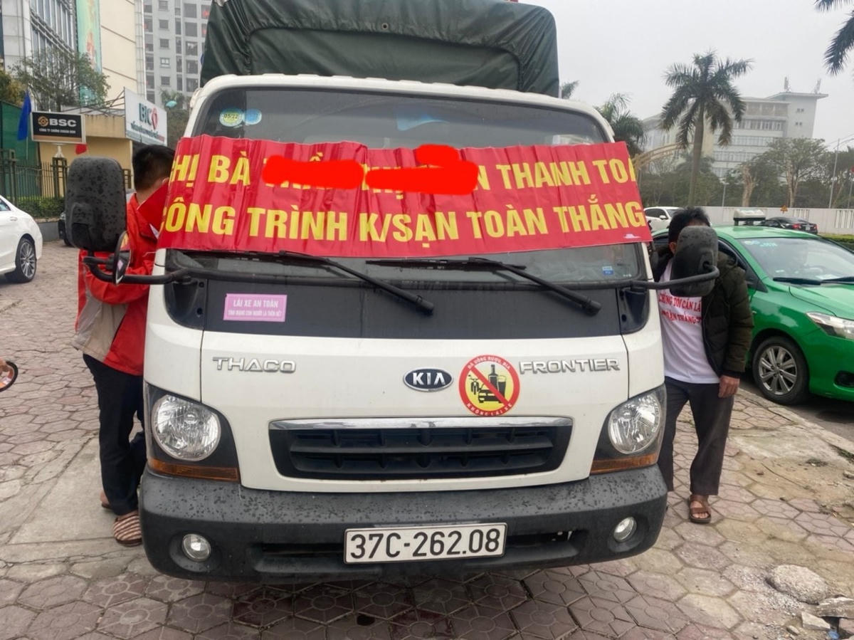 Chiếc xe dán băng rôn đòi nợ trước cổng khách sạn T.Th..