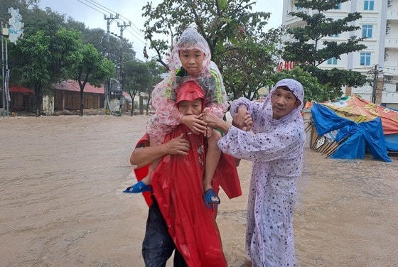 Người dân vượt qua điểm ngập để đưa trẻ nhỏ đến nơi an toàn.