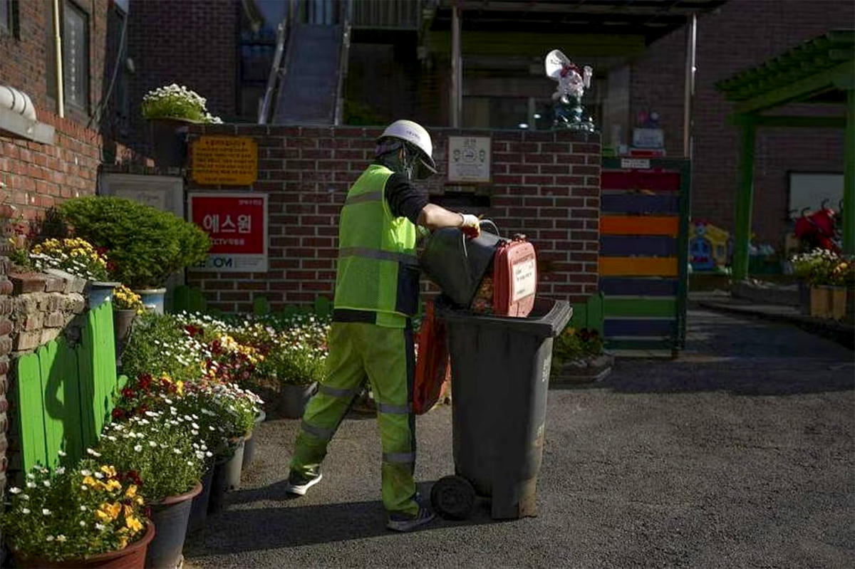 Một công nhân thu gom thức ăn thừa để tái chế tại một trường mẫu giáo ở Seoul. Ảnh: Nytimes.