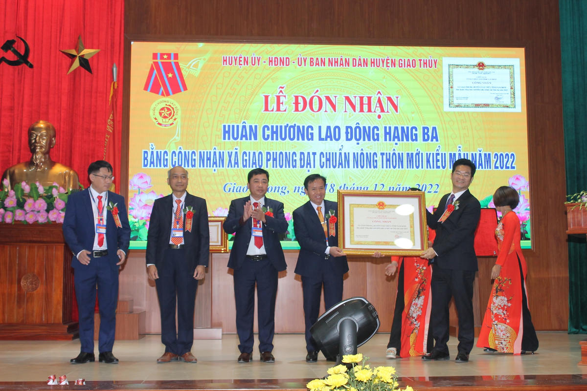 Thừa ủy quyền, Phó Chủ tịch Thường trực UBND tỉnh Nam Định Trần Anh Dũng (phải) trao Huân chương Lao động của Chủ tịch nước; trao Bằng công nhận xã đạt chuẩn "nông thôn mới kiểu mẫu" của Chủ tịch UBND tỉnh Nam Định tới đại diện Đảng bộ, chính quyền, nhân dân xã Giao Phong. 