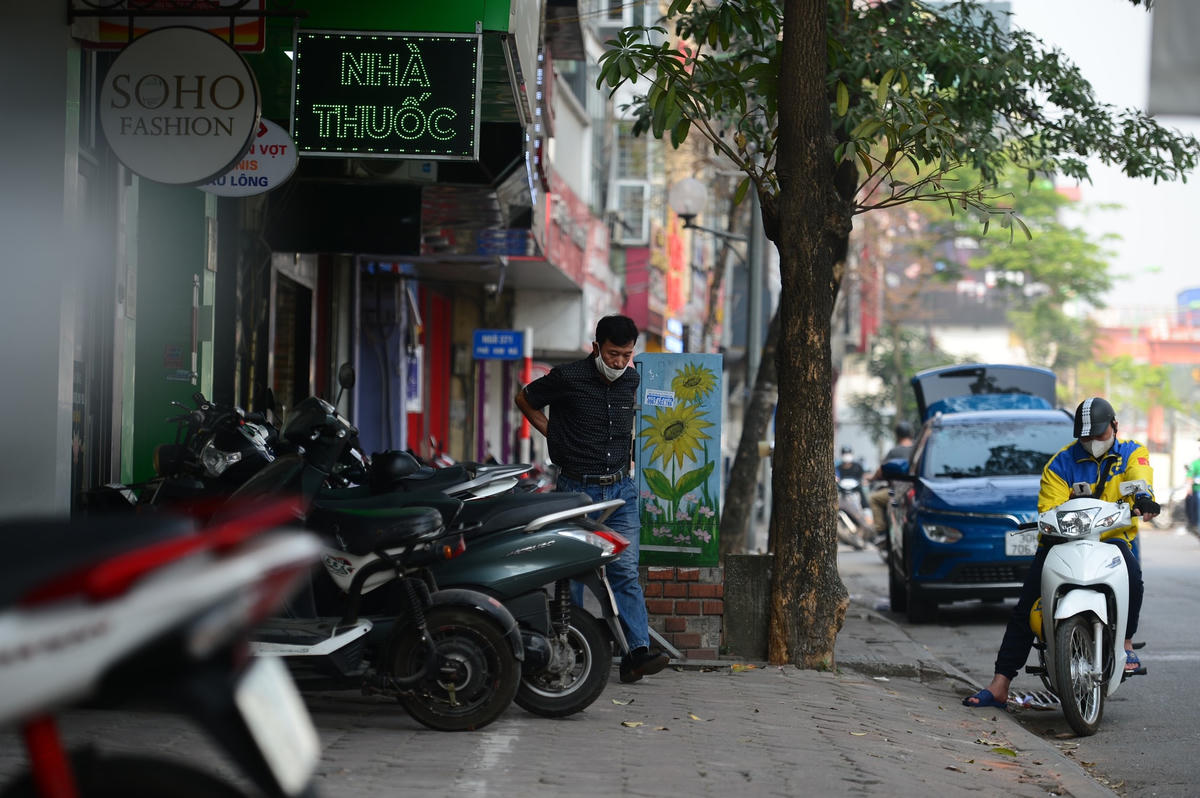 Người đàn ông phải luồn lách qua chiếc bốt điện và gốc cây để di chuyển trên vỉa hè.