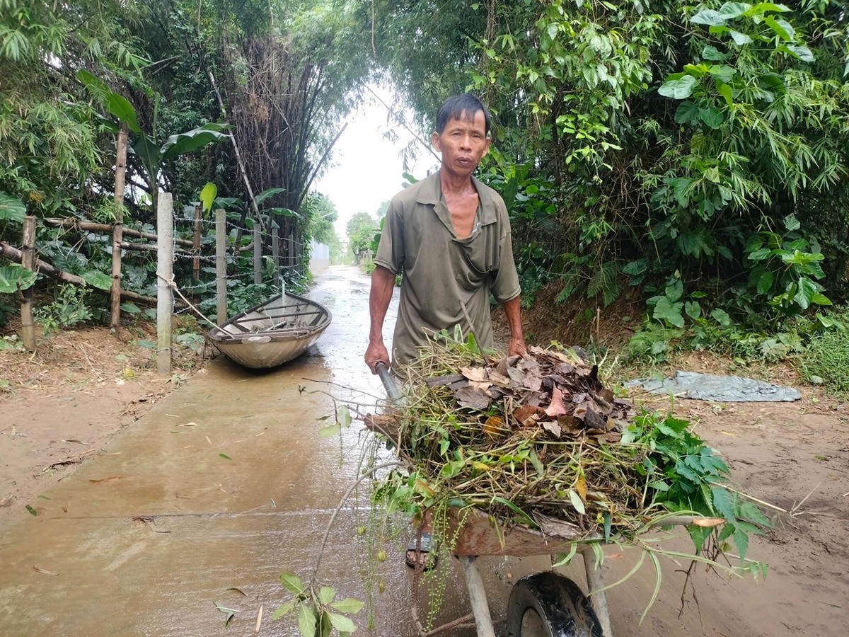 Ông Trương Văn Giọng dọn rác thải sau khi nước lũ rút xuống.