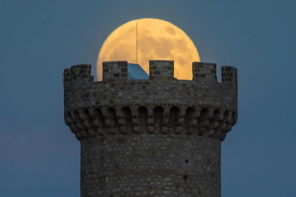 Mặt trăng dâu tây ẩn hiện sau một tòa tháp thời Trung cổ ở Santo Stefano di Sessanio ởI taly. Ảnh: Lorenzo Di Cola / NurPhoto / Rex / ShutterstockFacebookTwitter.