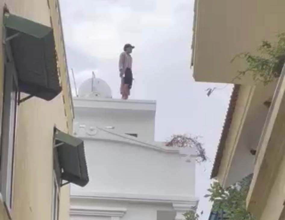 Nguyễn Ngọc Hùng đứng trên mái nhà và la hét.