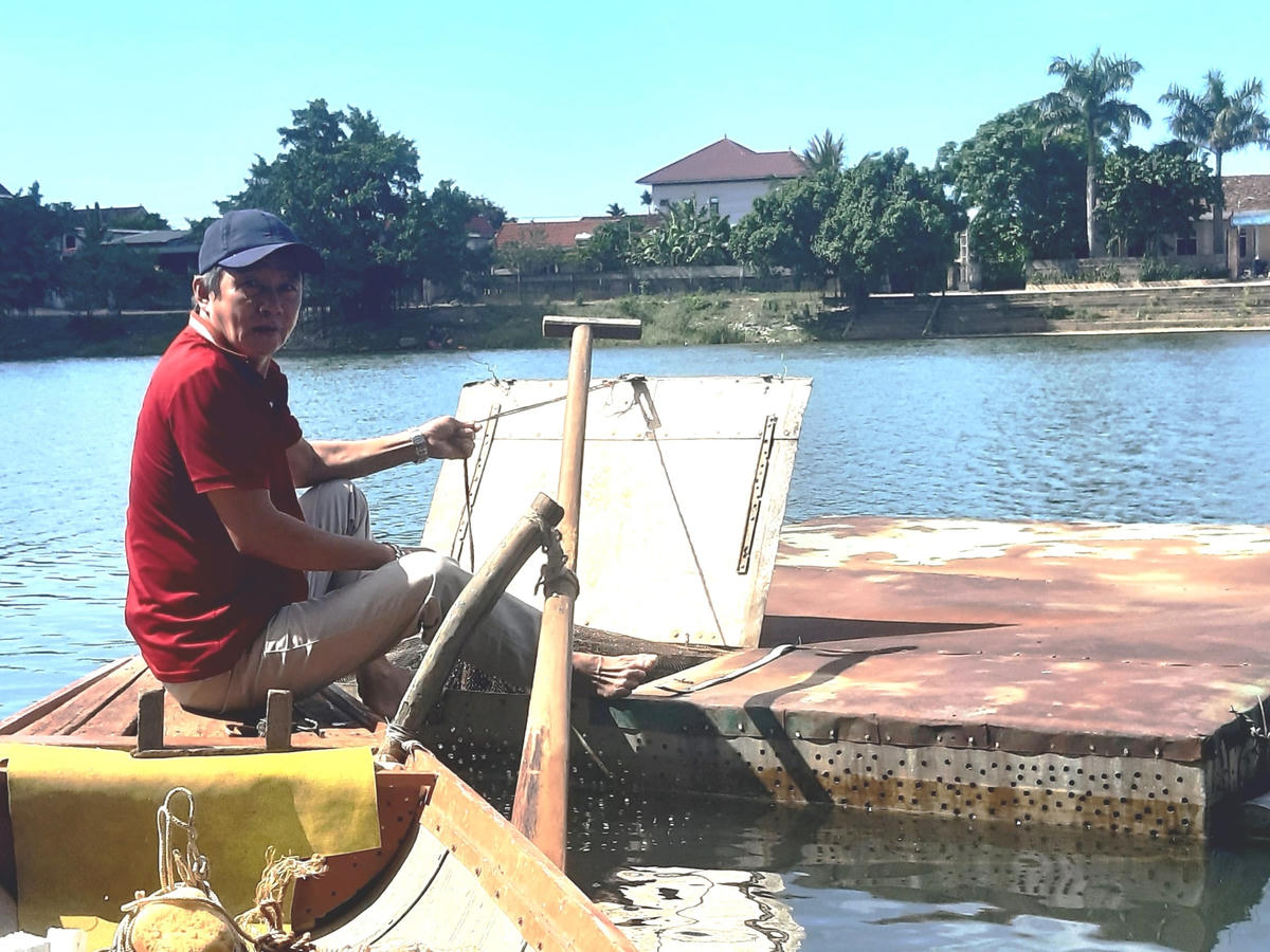 Ông Phạm Văn Liếc bên lồng cá chình của gia đình trên sông Kiến Giang.