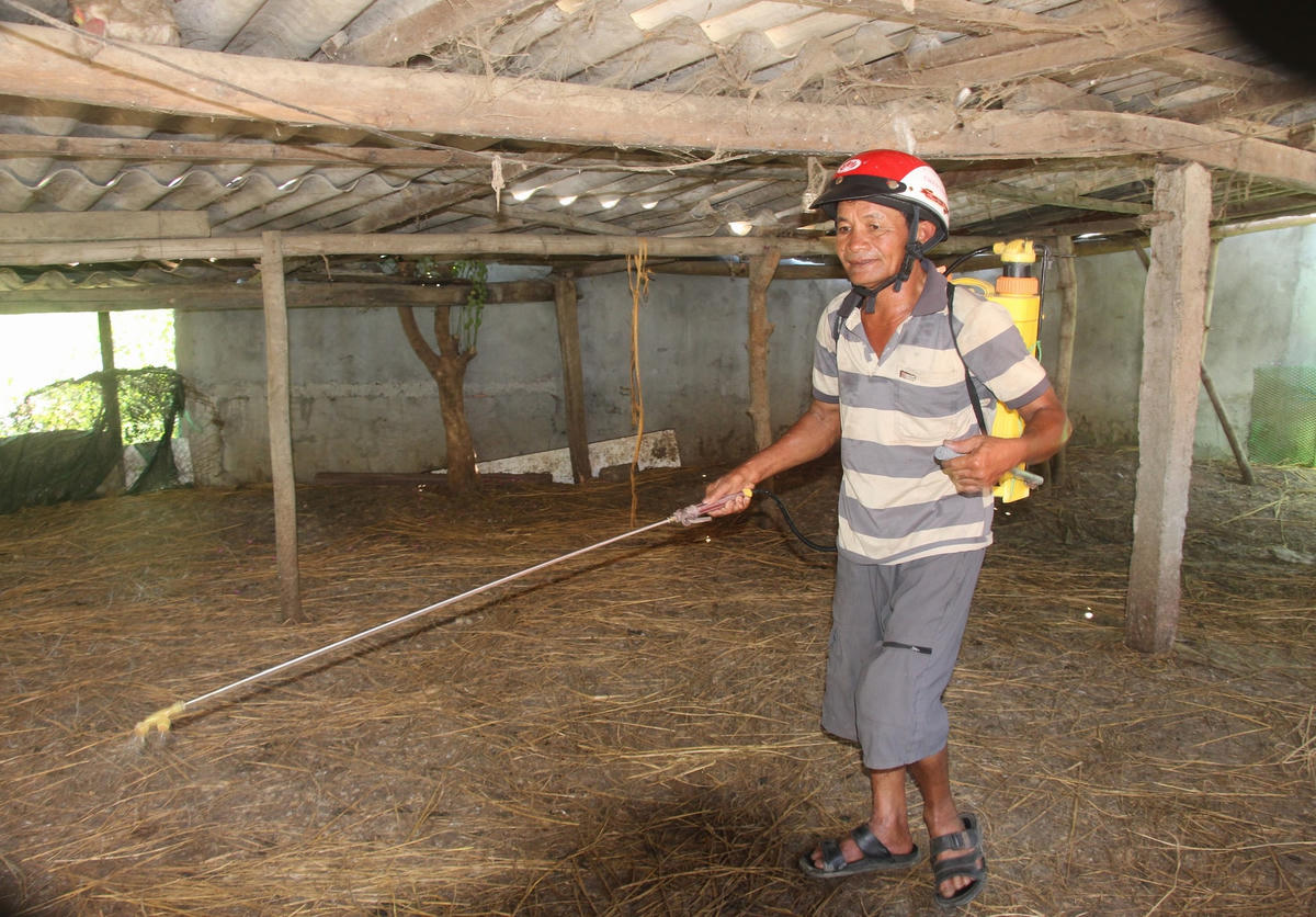 Ông Trần Văn Anh (thôn La Hà 3, xã Nghĩa Thương) phun thuốc khử trùng chuồng trại.