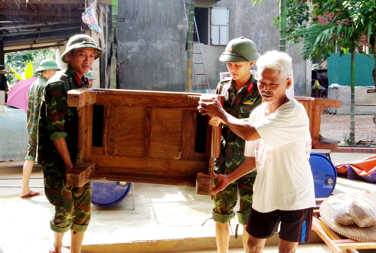 Cán bộ, chiến sĩ Trung đoàn 841 giúp đỡ gia đình ông Trần Hữu Khương (thôn Trung Tiến, xã Điền Mỹ) vận chuyển, kê kích lại vật dụng gia đình.
