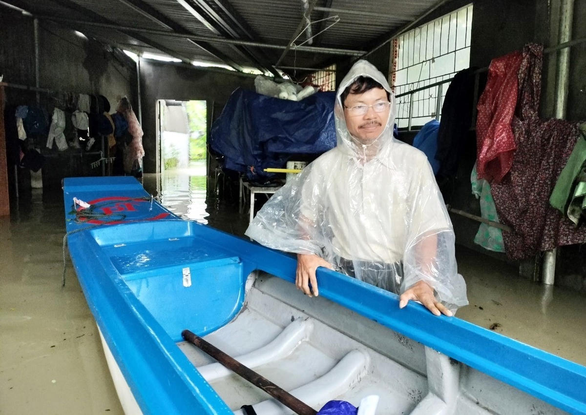 Ông Nguyễn Kiều Hưng chèo ghe đi lại ở khu dân cư ngập nước sâu.