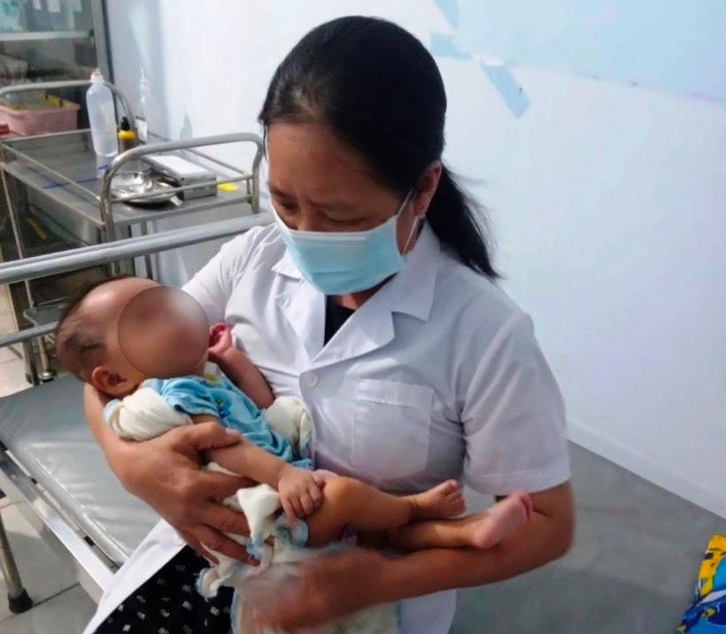Bé gái được nhân viên Trạm Y tế xã Quảng Thạch chăm sóc.