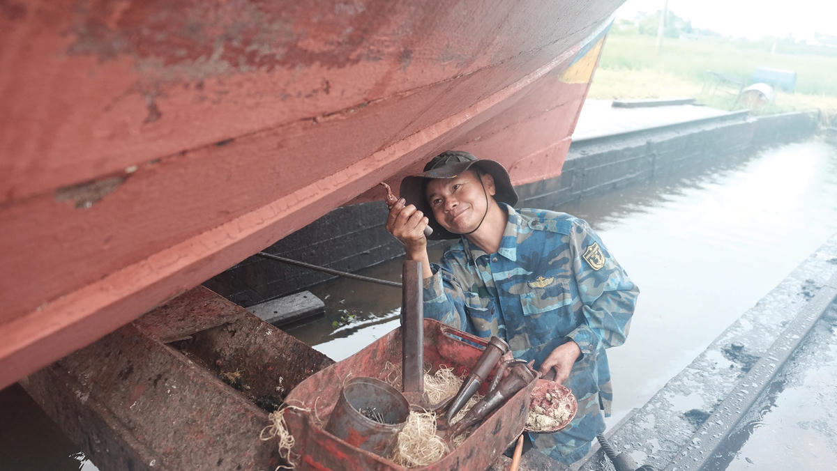 Thợ xảm sử dụng hỗn hợp keo đã trộn để bịt các rãnh hở trên thân thuyền.  