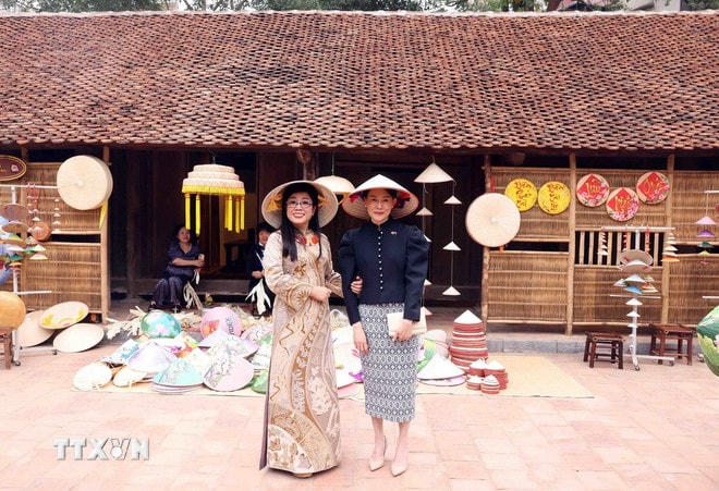 Bà Lê Thị Bích Trân, Phu nhân Thủ tướng Phạm Minh Chính cùng bà Loo Tze Lui, Phu nhân Thủ tướng Cộng hòa Singapore Lawrence Wong đội nón lá chụp ảnh lưu niệm tại Bảo tàng Dân tộc học Việt Nam. (Ảnh: Phạm Kiên/TTXVN) ttxvn-phu-nhan-viet-nam-singapore-6-resize.jpg