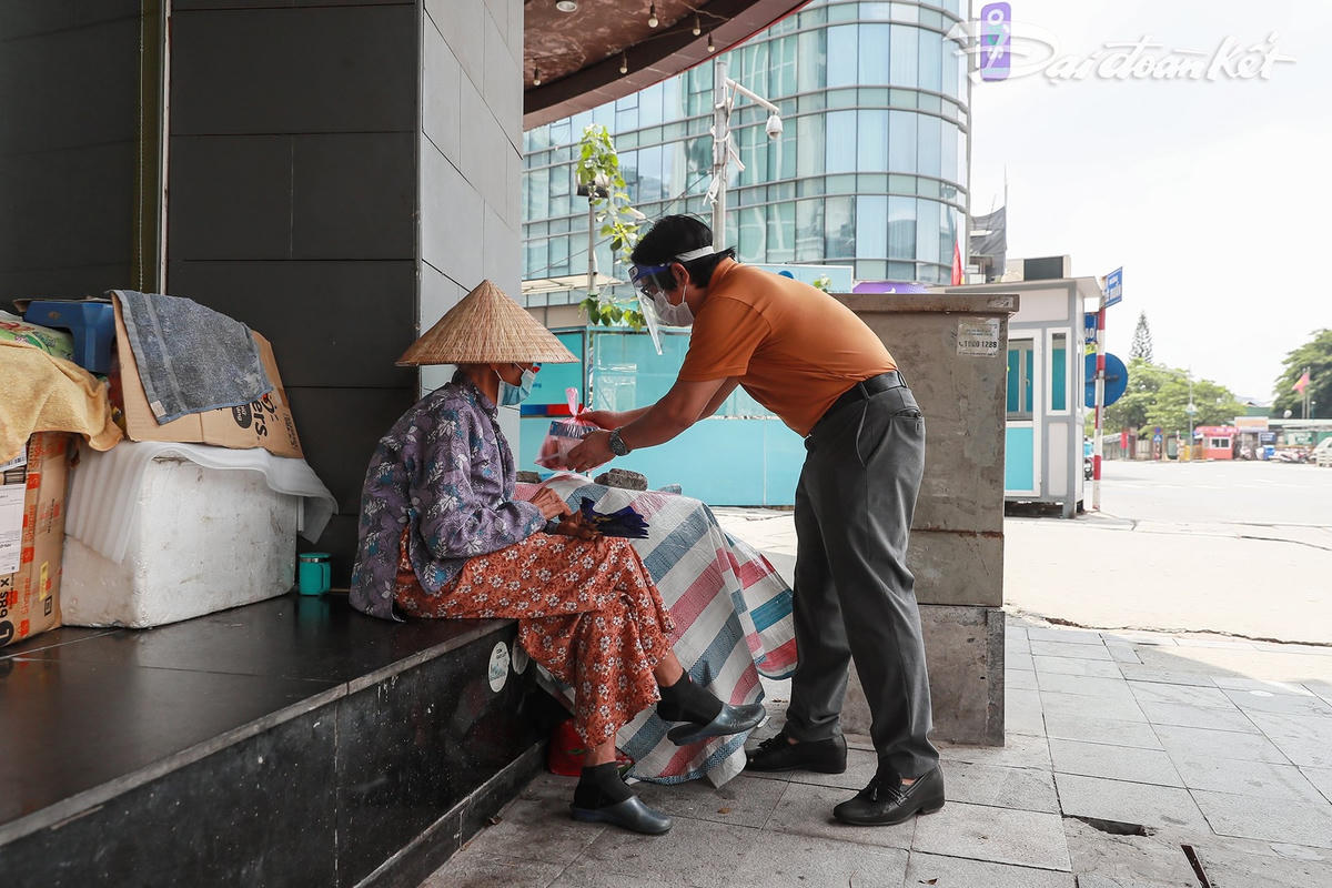 Một cụ già vô gia cư tại khu vực ga Hà Nội nhận suất cơm của Báo Đại Đoàn Kết. Ảnh: Quang Vinh. 