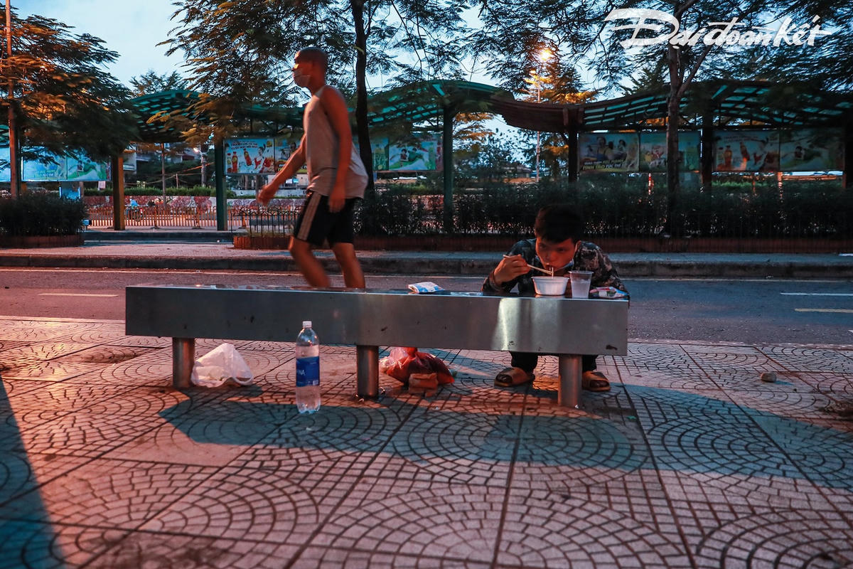 Trời đã dần tối, khi nhận được suất ăn, quay trở lại ghế đá, chia nhau từng góc, họ tranh thủ ăn ngay cho nóng. Ảnh: Quang Vinh. 
