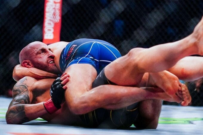 Brian Ortega (nằm trên) đang cố siết Alexander Volkanovski bằng đòn guillotine choke. Ảnh: AFP.