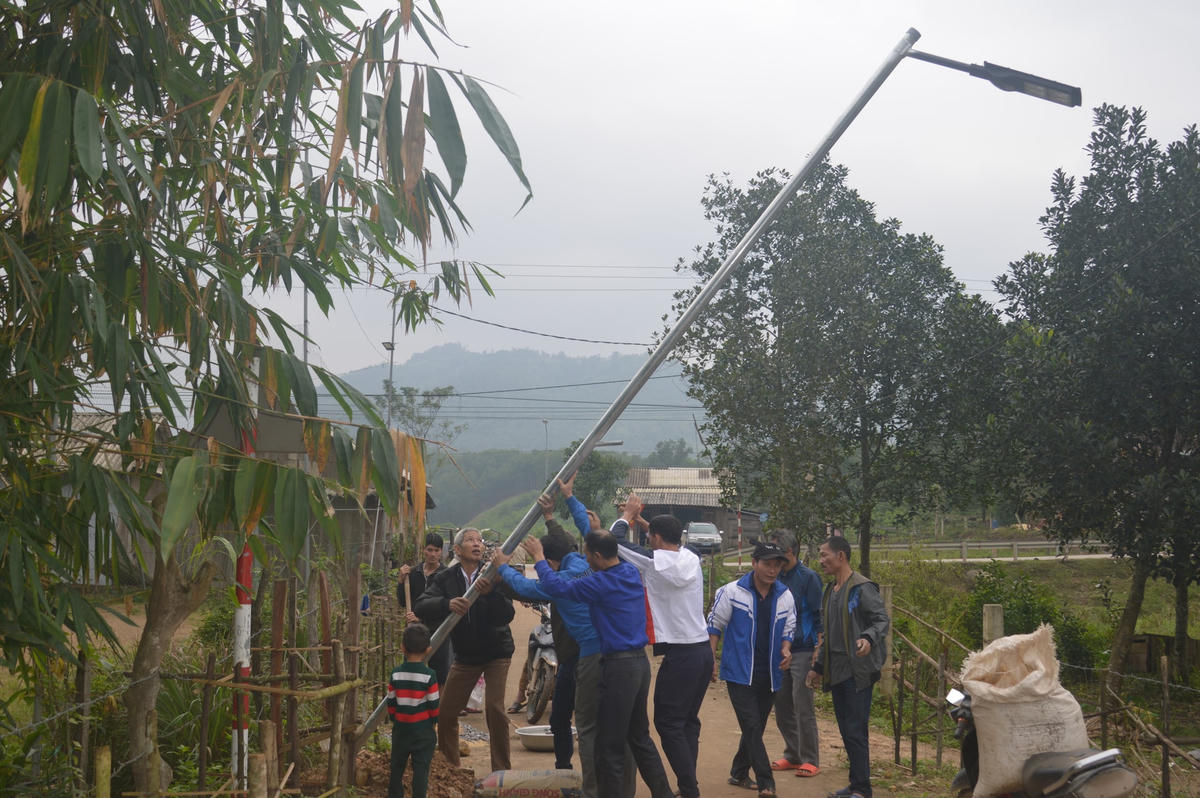 Người dân bản La Trọng 1 lắp đèn điện chiếu sáng trên đoạn đường kiểu mẫu.