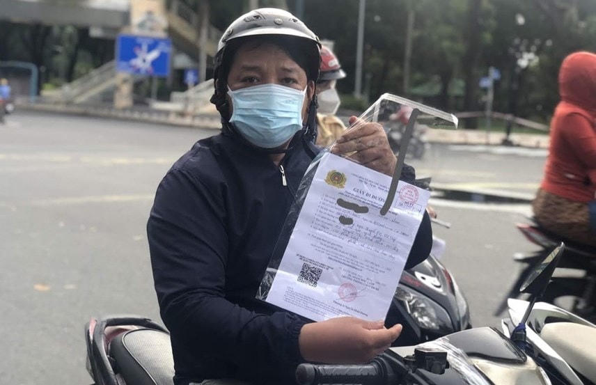 Người dân trình mẫu giấy đi đường mới do Công an TP HCM cấp.  