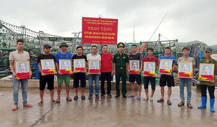 Đồn Biên phòng Quảng Đức tặng cờ Tổ quốc và ảnh Bác Hồ cho bà con ngư dân tại bến Cái Tó, xã Đường Hoa (Hải Hà).