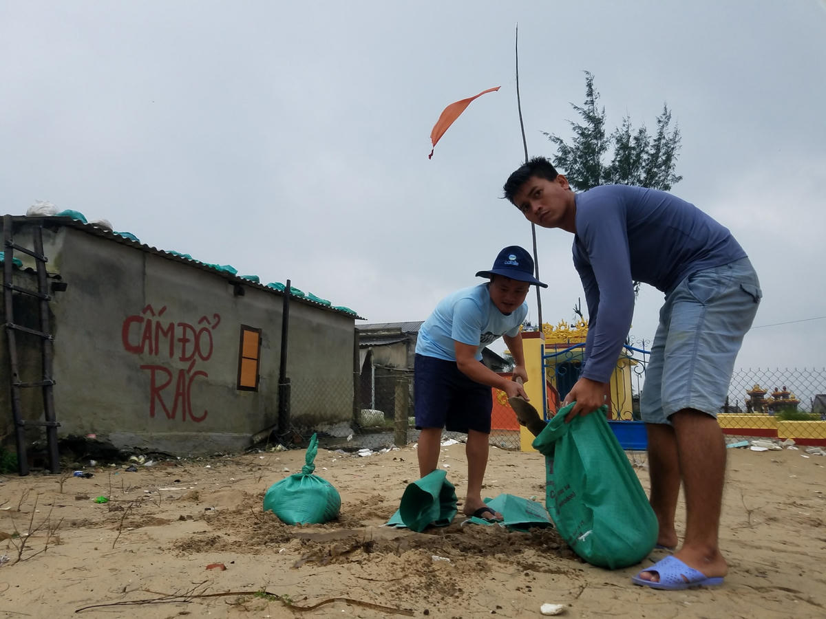 Người dân sử dụng các bao cát để giằng mái nhà chống bão.