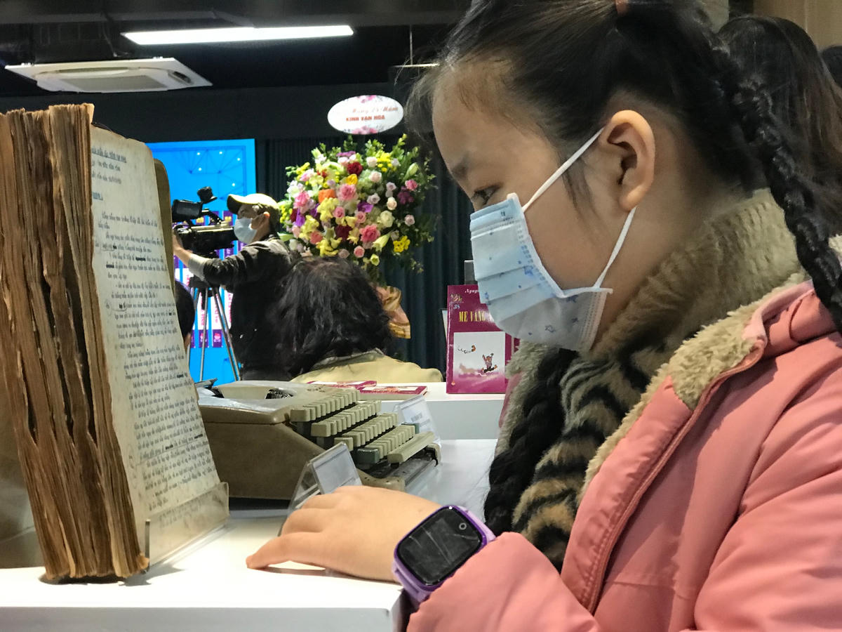 Độc giả nhỏ tuổi chăm chú xem bản thảo bộ sách "Kính vạn hoa".
