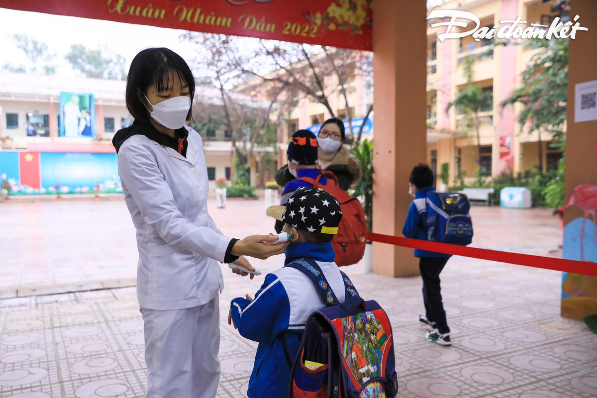 Y tế của trường cùng giáo viên đo thân nhiệt cho tất cả các em học sinh trước khi vào lớp học.