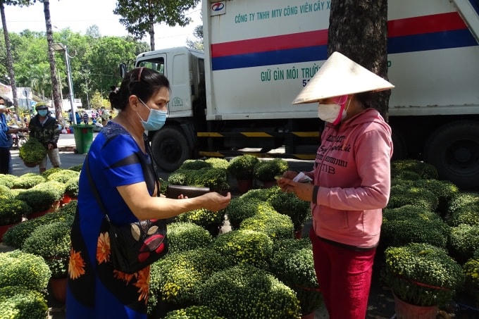 Một người dân (trái) tới mua hoa ủng hộ gia đình anh Thiện. Ảnh: Hà An.