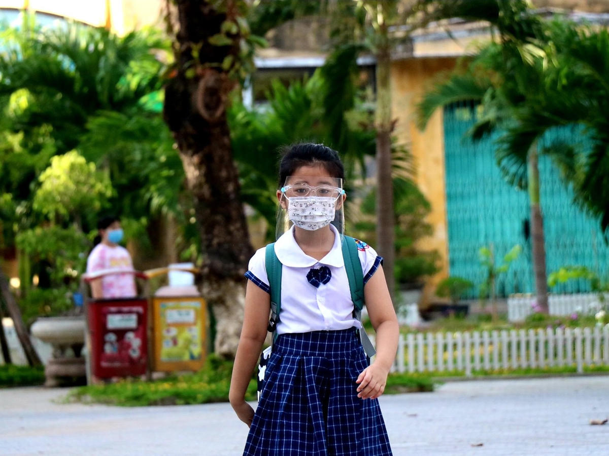 Một học sinh được bố mẹ trang bị tấm kính ngăn giọt bắn để đến trường, đảm bảo an toàn phòng, chống dịch.
