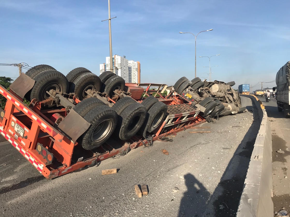 Xe đầu kéo chở 4 cuộn tôn lật nhào trên cầu vượt Sóng Thần. Ảnh: TL.