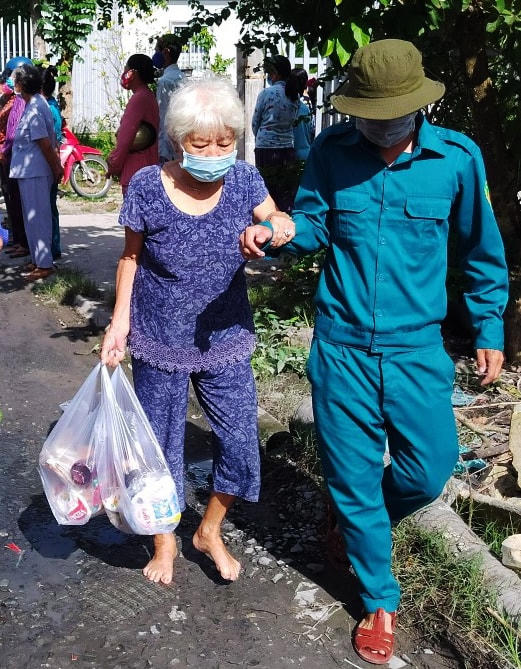 Lực lượng dân quân tự vệ ở địa phương hỗ trợ các cụ già yếu đến nhận hỗ trợ.