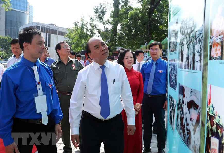 Thủ tướng Nguyễn Xuân Phúc thăm không gian trưng bày hình ảnh về lực lượng thanh niên xung phong. (Ảnh: Thống Nhất/TTXVN).