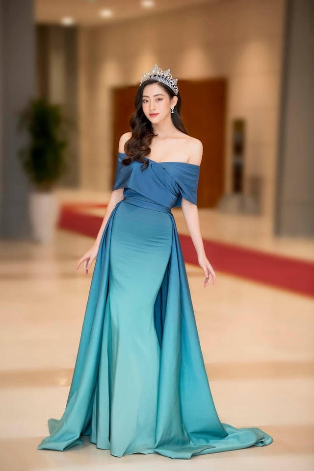 Hoa hậu Lương Thùy Linh xinh như công chúa khi đội vương miện, diện đầm dạ hội đơn giản. Bên cạnh thiết kế giúp khoe khéo vai trần gợi cảm, bộ váy này còn được nhà thiết kế sử dụng cách đi màu nhạt dần tạo điểm nhấn cho người đẹp 10X.