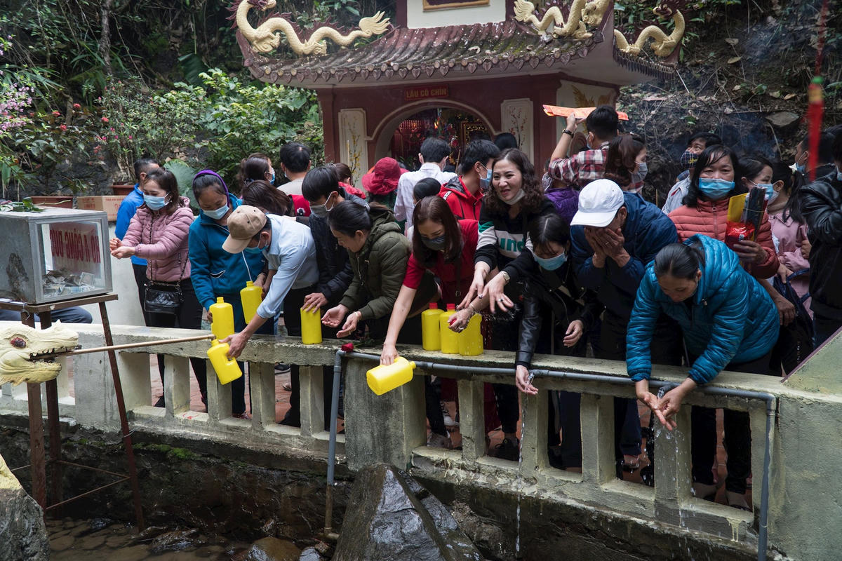 Người dân hứng "nước thánh" để mang về hoặc rửa mặt, rửa tay ngay tại chỗ với mong muốn năm mới gặp nhiều tài lộc, may mắn.