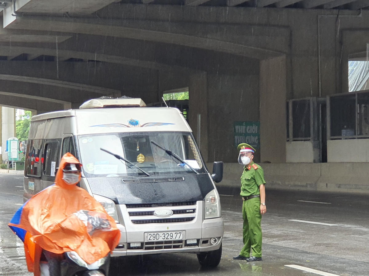 Một chiến sĩ công an đang "đội mưa" kiểm tra giấy tờ của phương tiện.